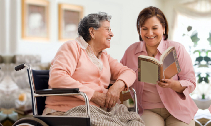 caregiver reading book to senior woman