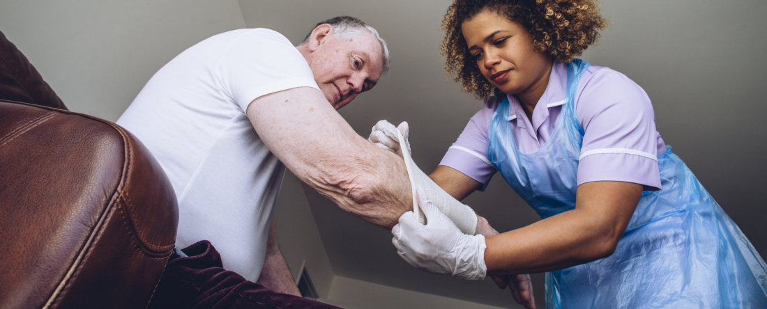 caregiving nurse putting a bandage on a senior mans arm